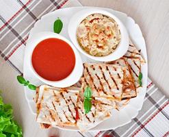 Mexican Quesadilla sliced with vegetables and sauces on the table photo