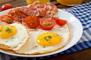 English breakfast - toast, egg, bacon and vegetables in a rustic style on wooden background photo