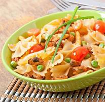 pasta farfalle con mariscos, tomates cherry y guisantes verdes foto