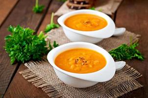 Delicious cream of pumpkin soup in a bowl on wooden table photo