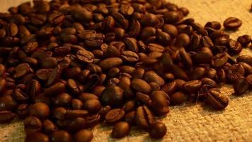 grãos de café torrados caindo para grãos de café na mesa pela manhã. câmera lenta video