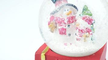 Close up of Christmas tree and snowman in snow globe on white background video