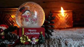 arbre de noël, jouet du père noël et bonhomme de neige dans une boule à neige avec des bougies allumées pour le nouvel an ou les vacances de noël internationales sur fond de bois