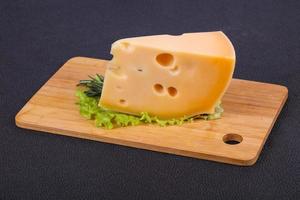 queso maasdam en el tablero hojas de ensalada servidas foto
