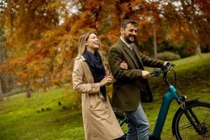 Young couple in the autumn park with electrical bicycle photo