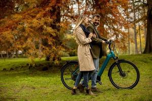 pareja joven, en, el, otoño, parque, con, bicicleta eléctrica foto