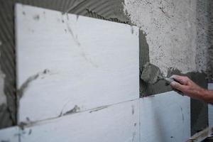worker installing big ceramic tiles photo