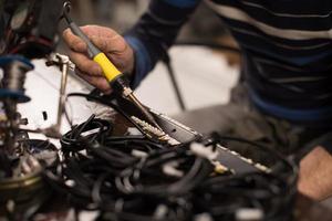 Industrial worker man soldering cables of manufacturing equipment in a factory. Selective focus photo