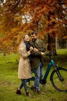 pareja joven, en, el, otoño, parque, con, bicicleta eléctrica foto