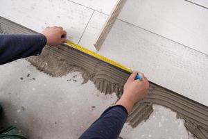 worker installing the ceramic wood effect tiles on the floor photo