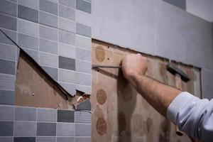 worker remove demolish old tiles in a bathroom photo