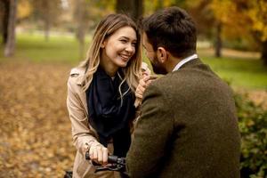 Young couple in the autumn park with electrical bicycle photo