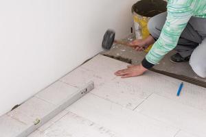 worker installing the ceramic wood effect tiles on the floor photo