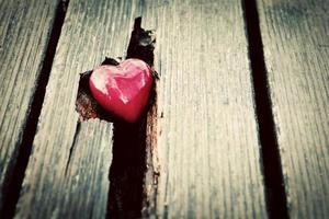 corazón rojo en la grieta del tablón de madera. símbolo de amor foto