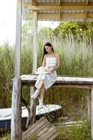 mujer joven relajándose en el muelle de madera en el lago tranquilo foto