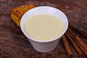 Condenced milk in the bowl with sinnamon and pastry photo