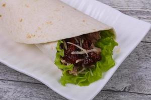 Tortilla with tuna, salad and dried tomato photo