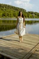 Young woman walking on the wooden pier at the calm lake photo