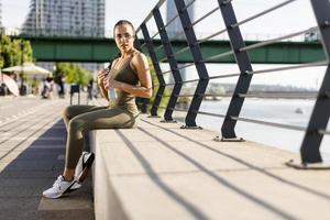 Young woman taking a break during exercise on the river promenade photo
