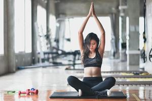 sport asian woman practicing yoga lesson, breathing, meditating, doing Ardha Padmasana exercise, working out in the gym photo