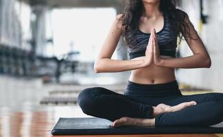 deporte mujer asiática practicando clases de yoga, respirando, meditando, haciendo ejercicio ardha padmasana, haciendo ejercicio en el gimnasio foto