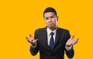 Asian businessman showing signs bored mood unhappy stubborn unsatisfied, dissatisfaction unfair Isolated on yellow background. Business concept. photo