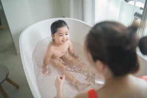 niña asiática feliz bañándose y lavándose el cabello con la madre en casa, baby shower infantil asiático. concepto de familia de bebé.