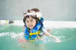 Mother and daughter swimming playing in the pool, smiling and laughing. Having fun in the pool at the resort hotel, family happy concept. photo