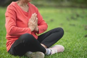 Senior asian woman practicing yoga lesson, breathing, meditating in garden. Working out, Well being, wellness concept photo