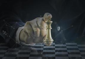 Hand of businessman holding the golden king chess to fighting silver king chess to play successfully in the competition with technology network background. Management or leadership strategy concept. photo