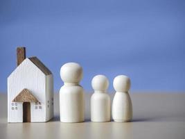 Three wooden figures people standing nearby of tiny wooden house. Concept for family, loan, property ladder, financial, mortgage, real estate investment, taxes and bonus. photo