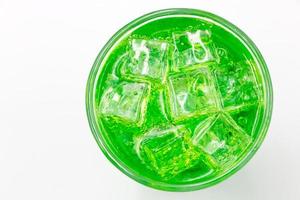 Green sparkling water with Ice in glass over white background. photo