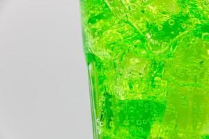 Green sparkling water with Ice in glass over white background. photo