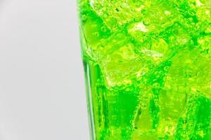 Green sparkling water with Ice in glass over white background. photo