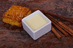 Condenced milk in the bowl with sinnamon and pastry photo