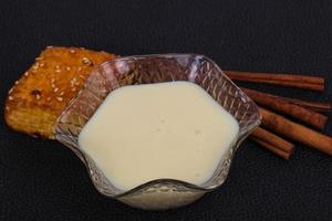 Condenced milk in the bowl with sinnamon and pastry photo