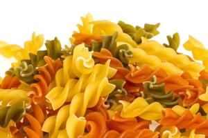 Uncooked pasta fusilli in different colours, white background photo