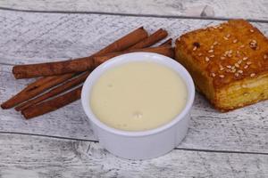 Condenced milk in the bowl with sinnamon and pastry photo