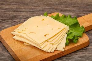 Sliced yellow cheese over board photo