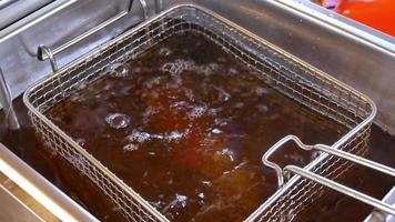 Fryer from the food net is lowered into boiling oil in an outdoor fast-food restaurant video