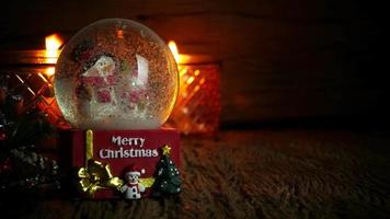 kerstboom, kerstman speelgoed en sneeuwpop in sneeuwbol met brandende kaarsen voor nieuwjaar of kerstvakantie international op houten achtergrond