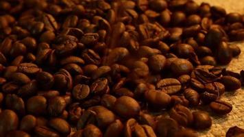 Roasted coffee beans falling down to coffee beans on table in the morning.Slow motion video