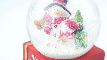 Close up of Christmas tree and snowman in snow globe on white background video