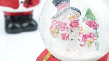 närbild av julgran och snögubbe i snöglob på vit bakgrund