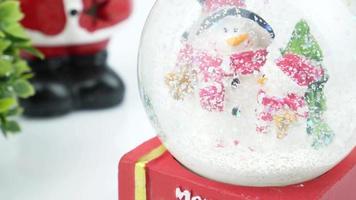Close up of Christmas tree and snowman in snow globe on white background video