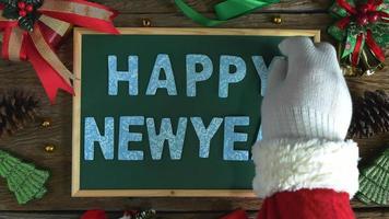 Santa's hand legde houten letters voor het woord gelukkig nieuwjaar op het bord. video