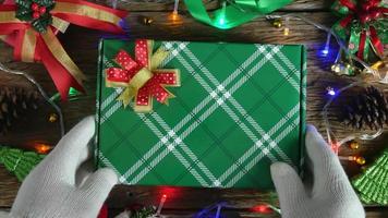 caja de regalo en patrón verde sobre una mesa de madera. que está decorado con adornos navideños