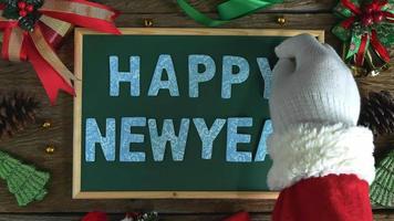 die hand des weihnachtsmanns legte holzbuchstaben für das wort frohes neues jahr auf die tafel. video