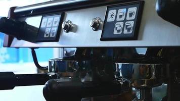 les mains d'une jeune femme barista appuyaient sur le bouton de démarrage de la machine à café