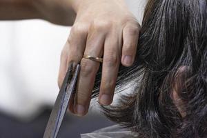 new normal girl left hand hold gray hair for cutting by Scissors cut the golden women hairs photo